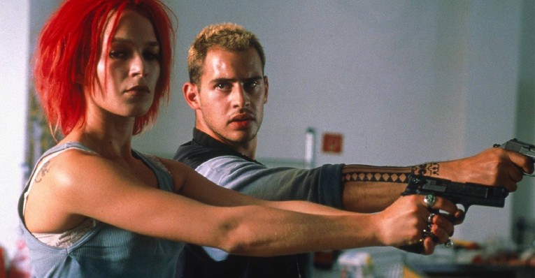 Two people poiting pistols: red haired girl and blond male