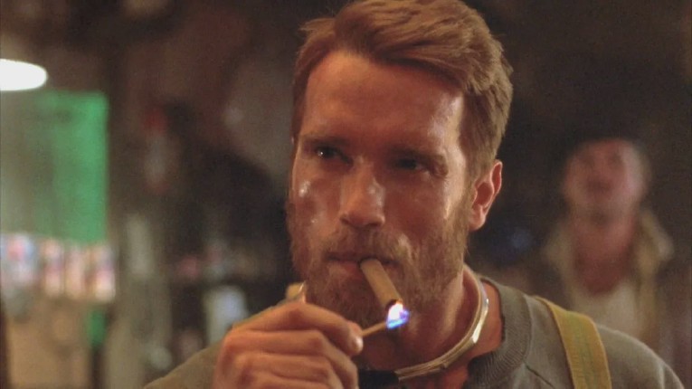 Face of a white, bearded man lighting a cigarette